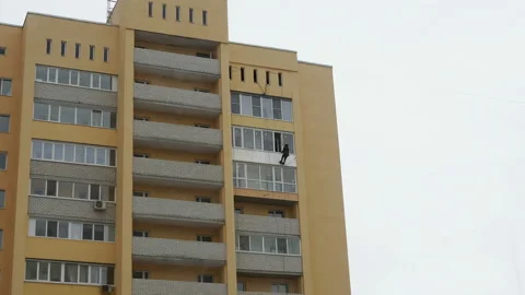 Climber worker hanging on ropes for balcony insulation of high rise building Stock Footage 149967613