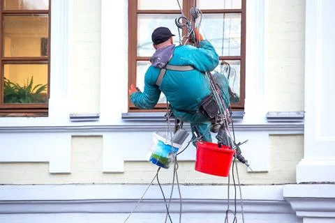 Climber worker maintains a window and facade of a residential building in rep Stock Photos