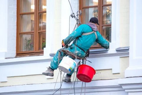 Climber worker serves the window and the facade of a residential building und Stock Photos