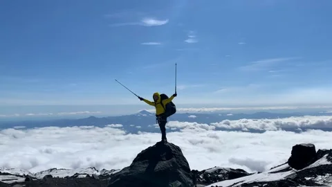 Climber in a yellow jacket at the top of the mountain Stock Footage 140373866