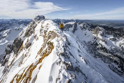 Climbers on a narrow rocky snowy ridge behind peak crow view of mountain Stock Photos