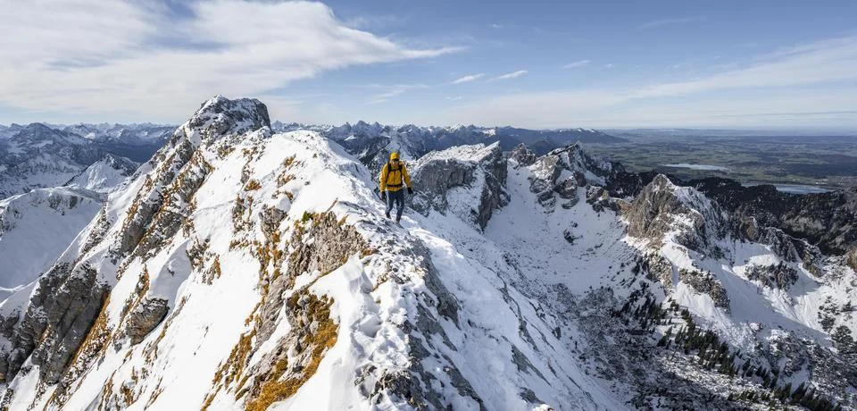 Climbers on a narrow rocky snowy ridge behind peak crow view of mountain Stock Photos
