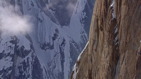 Climbers scaling a massive rock wall in the mountains 스톡 동영상 335099017
