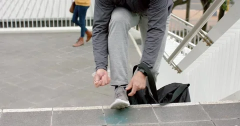 Climbing granite step man tightening sneaker laces while friend in yellow jacket Stock Footage 336609191