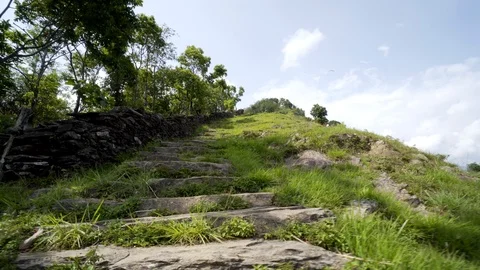 Climbing up stone steps on grass hill with paraglider above Stock Footage 91171540