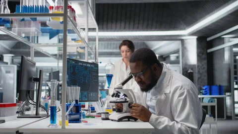 Clinical microbiologist operating compound microscope, recording findings Stock Footage 320740599