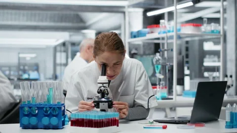 Clinical microbiologist using compound microscope for detailed cellular analysis 库存影片 325819145
