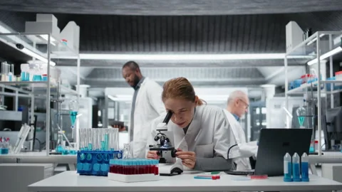 Clinical microbiologist using compound microscope for detailed cellular analysis Stock Footage 326012525