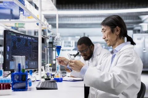 Clinical microbiologist using PC, looking at 3D molecular model 스톡 사진