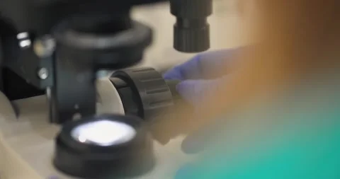 Clinician adjusting knobs to focus on a microscope 動画素材 249988746