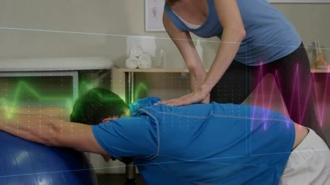 Clinician leaning over patient on exercise ball placing hands causing shifting Stock Footage 330161637