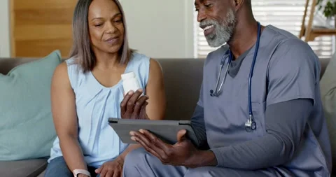 Clinician with stethoscope picking bottle on table, using tablet, explaining Stock Footage 336305904