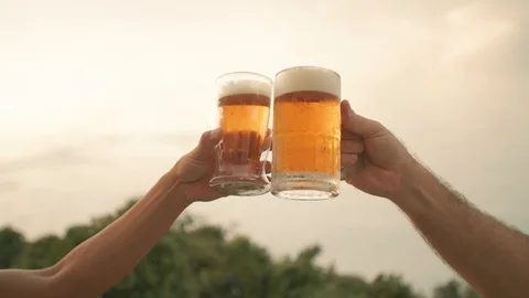 Clinking beer glasses at sunset man and woman hands only Stock Footage 124769809