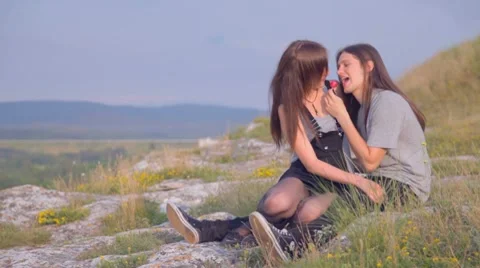 CLIP EDIT Young man and woman sitting in weeds, sharing lollipop, kissing Stock Footage 8367077