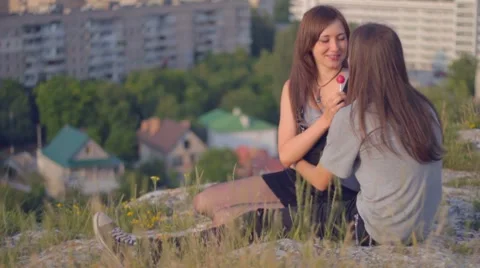 CLIP EDIT Young romantic couple sitting on slope, sharing lollipop, s Stock Footage 8367121