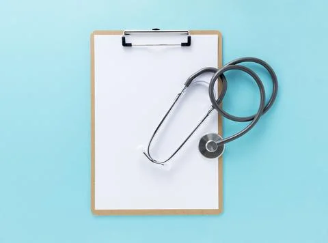 A clipboard and stethoscope with white paper on it on a blue background Stock Photos
