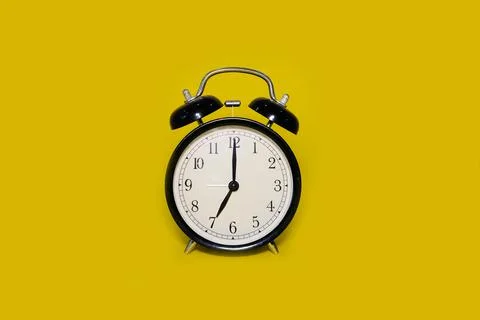 Clock alarm clock on a bright yellow background Stock Photos