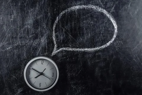 Clock and chalked dialog cloud on blackboard Stockfoto's