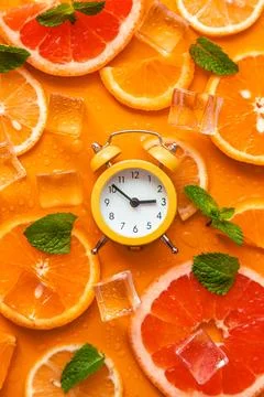 Clock and citruses summer time concept. Selective focus. Stock Photos