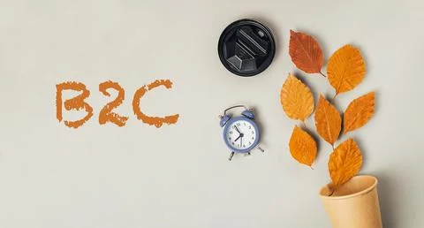 Clock and a cup are on a table with the word B2C written in orange Stock Photos