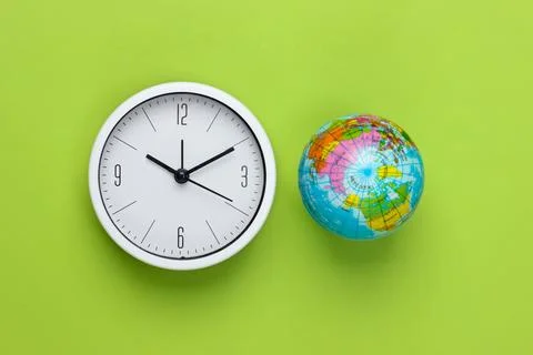 Clock and globe on a green background. World time. Top view Stock Photos