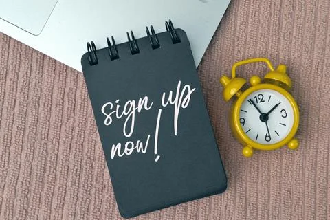 Clock and notebook written with text SIGN UP NOW! Foto stock