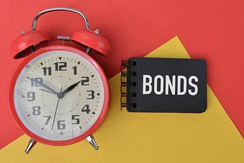 Clock and notebook written with text BONDS. Top view. Stock Photos