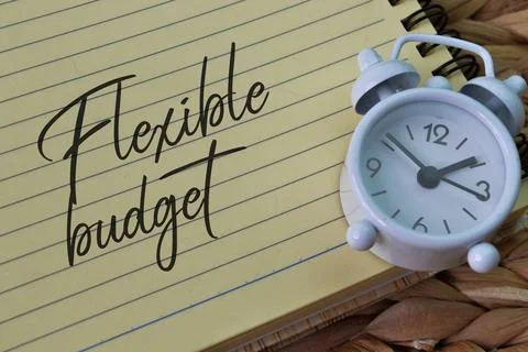 Clock and notebook written with text FLEXIBLE BUDGET. Stock Photos