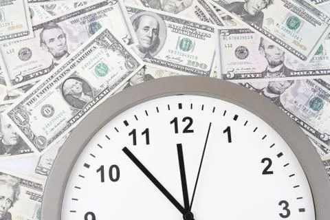 Clock on assorted American banknotes. Time is money idea Stock Photos
