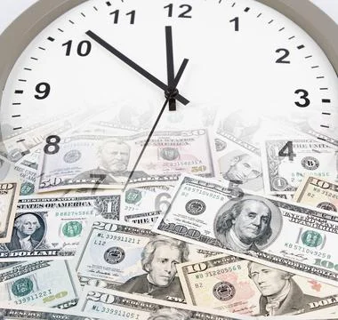 Clock on assorted American banknotes. Time is money idea Stock Photos
