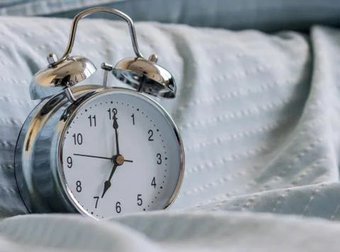 Clock on the bed in the morning. Stock Photos