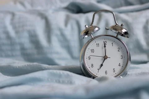 Clock on the bed in the morning. Stock Photos