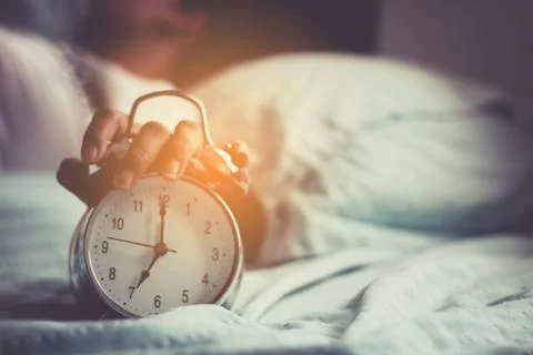 Clock on the bed in the morning. Stock Photos