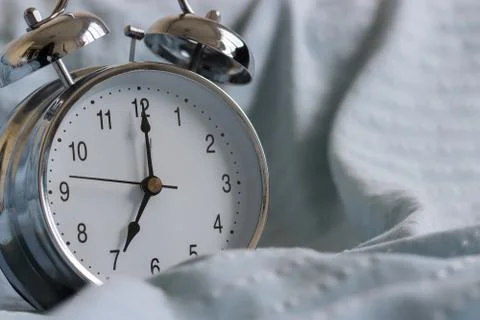 Clock on the bed in the morning. Stock Photos
