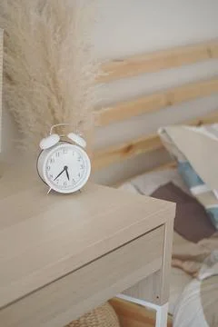 Clock on bedside table in simple bedroom setting Stock Photos