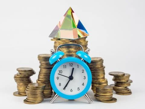 The clock, behind them are stacks of coins on which the glass pyramid stands Stock Photos