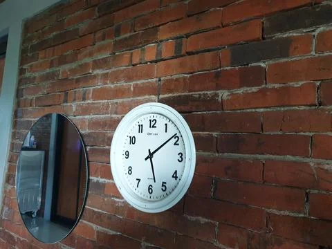 Clock in the brick wall at between mirror Foto stock