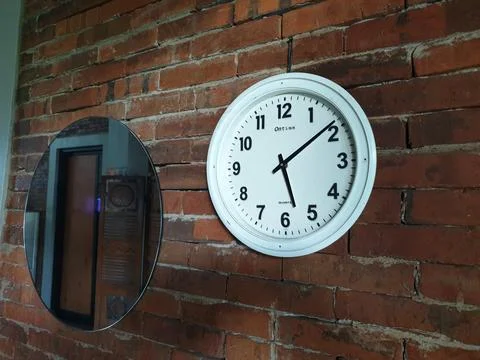 Clock in the brick wall at between mirror Stock Photos