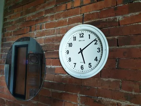 Clock in the brick wall at between mirror Foto stock