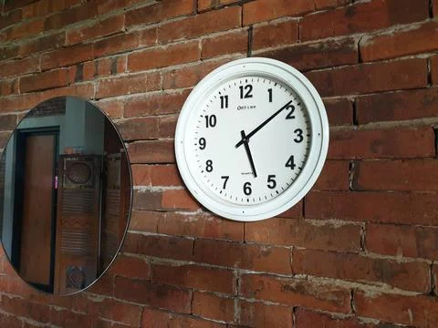 Clock in the brick wall at between mirror Foto stock