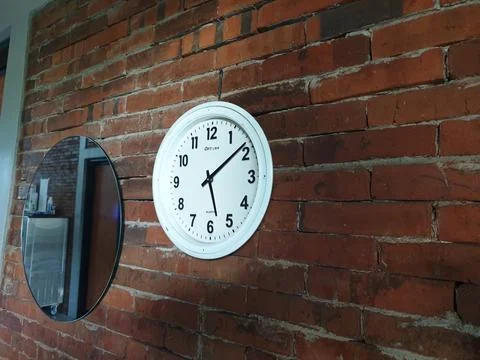 Clock in the brick wall at between mirror Foto stock