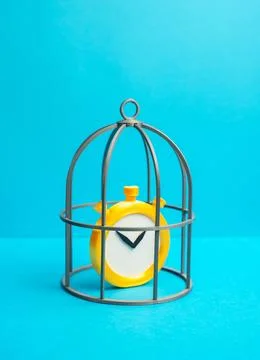 A clock in a cage. Concept of time restriction and limited freedom. Symbol .. Stock Photos