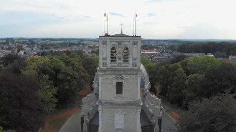 Clock on cathedral with flags on  in park flying towards with drone Aerial Stock Footage 123137405