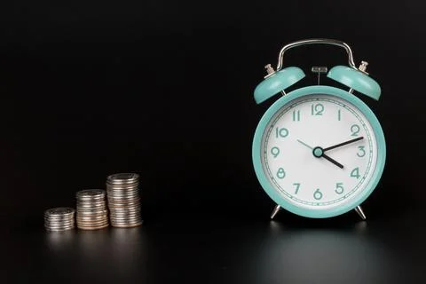 Clock with coins on black background.The concept of increasing profitability Foto stock