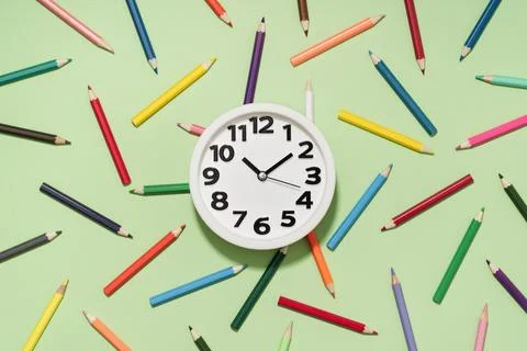 Clock on Colored Pencils background pattern. Back to School Stock Photos