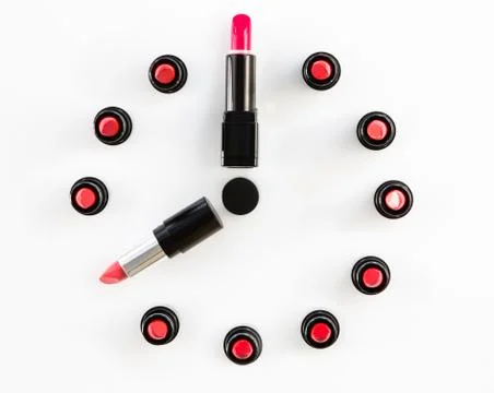 Clock face and arrows on white background made from lipsticks Stock Photos