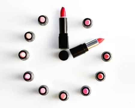 Clock face and arrows on white background made from lipsticks Stock Photos