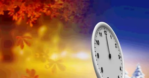 A clock face standing against a background of autumn leaves and winter landscape Fotos de archivo