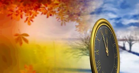 A clock face standing against a background of autumn leaves and winter landscape Fotos de archivo