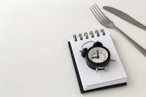 Clock with fork and knife, intermittent fasting and weight loss plan concept Stock Photos